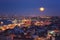 Night view of Istanbul, scenic cityscape with buildings in lights, bridge, bay and blue sky with full moon, Turkey