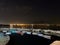 Night view of small pier with coloured boats on city lights