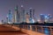 Night view to Dubai iconic skuscrappers panorama. Amazing illumination of the buildings reflected in the Gulf