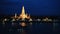 Night view of Wat Arun across Chao Phraya River with boat in Bangkok