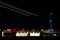 Nightime view of the Atlanta international airport with air traffic control and streaks of planes taking off over bright hangars