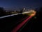 Nighttime highway illuminated by glowing light trails on the asphalt. Tegelen, Netherlands.