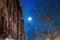 Nighttime shot of the moon, trees, and building facade in Harlem, New York, NY, USA