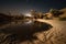 nighttime stars and moon reflected in the desert sand