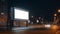 Nighttime street scene with billboard and lanterns. Blank roadside billboard at night in the city