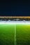 Nighttime view of an illuminated soccer field in a stadium with spectators in the stands