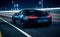 Nighttime view of sports car on city highway, seen from behind, with urban landscape and city lights in background. Dynamic and