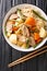 Nikujaga or meat and potatoes is an easy comforting Japanese stew made with pork, potatoes and carrots close up in bowl. Vertical