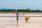 Nin, Croatia - 8 July 2021: Man picking up salt in the swamp and filling the wheelbarrow. Salt farmer harvesting the salt. Sea