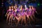 Nine beautiful showgirls in purple costumes posing