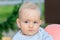 A nine-month-old boy with blond hair and blue eyes looks thoughtfully into the distance