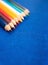 Nine multicolored pencils on a blue felt background. Different colored pencils with space for text. Back to school. Art lessons