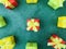 Nine square red, green, and yellow gift boxes on a green textured background. Aerial view.