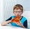 Nine-year-old boy with glasses eats pizza