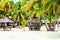 Nipa huts on the white coral sand beach surrounded with palms