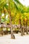 Nipa huts on the white coral sand beach surrounded with palms