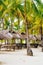 Nipa huts on the white coral sand beach surrounded with palms