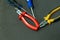 Nippers rubber handles with red and blue screwdriver on dark background desktop repair tool kit