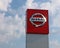 Nissan logo in the car dealership of the area, against a blue sky with clouds. It is the symbol of t