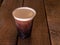 Nitrogen infused cold brew coffee in a clear plastic cup on a wood table.