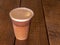 Nitrogen infused cold brew coffee in a plastic cup on a wooden background.