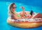 Njoying suntan Woman in bikini on the inflatable mattress in the swimming pool using digital tablet and credit card.