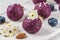 No bake blueberry and acai energy bites or balls made of nuts, coconut flakes and dates served with flowers. close up