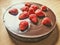 No baked sweet chocolate rounded cake with cookies, poppy seeds and strawberries