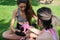 No binary person helping woman to put on muay thai hand wraps sitting on grass in a park