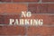 No car parking sign sprayed on red brick wall with yellow paint