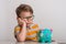 No cash money. Little caucasian kid banking money on piggy bank as wealth savings with angry face, negative sign showing