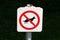 No dogs allowed white metal sign with black image of dog crossed with red line mounted on strong metal pole with dark green grass