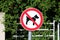 No dogs allowed white round metal sign with black image of dog crossed with red line mounted on metal pole placed in local park