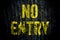 â€œNo Entryâ€ warning sign in yellow letters painted over dark grungy grey concrete wall