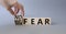 No fear vs big fear symbol. Businessman hand turnes wooden cubes and changes word Big fear to No Fear. Beautiful grey background.