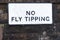 No fly tipping sign on council estate wall