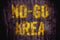 â€œNo-Go Areaâ€ danger warning sign in yellow letters painted over dark grungy concrete wall texture background