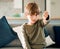 No kid enjoys being alone and hungry. Portrait of a cute little boy showing the thumbs down while sitting on a sofa at