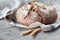 No knead handmade loaf on cutting board on wood with linen towel, spelt ears. German Bauernbrot means Rustic Farmers