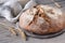 No knead handmade loaf on cutting board on wood with linen towel, spelt ears. German Bauernbrot means Rustic Farmers