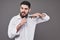 No more beard. Portrait of handsome young man cutting his beard with scissors and looking at camera while standing