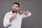 No more beard. Portrait of handsome young man cutting his beard with scissors and looking at camera while standing