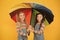 No more rain. Good mood at any weather. small girl under colorful umbrella. two happy kids yellow wall. children enjoy