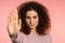 No, never, pretty curly woman disliking and rejecting gesture by stop palm sign