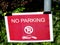 No parking or parking prohibited sign printed on red paper mounted on light post. lush green background