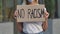 NO RACISM on a cardboard poster in the hands of female protester activist. Closeup of poster and hand. The peaceful life