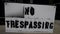 No Trespassing sign swinging across sidewalk