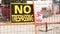 no trespassing warning 24 hour video surveillance signs on orange locked gate