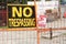 no trespassing warning 24 hour video surveillance signs on orange locked gate. p