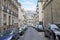 Nobody in Paris street, ancient buildings and car parked in a summer day in France
